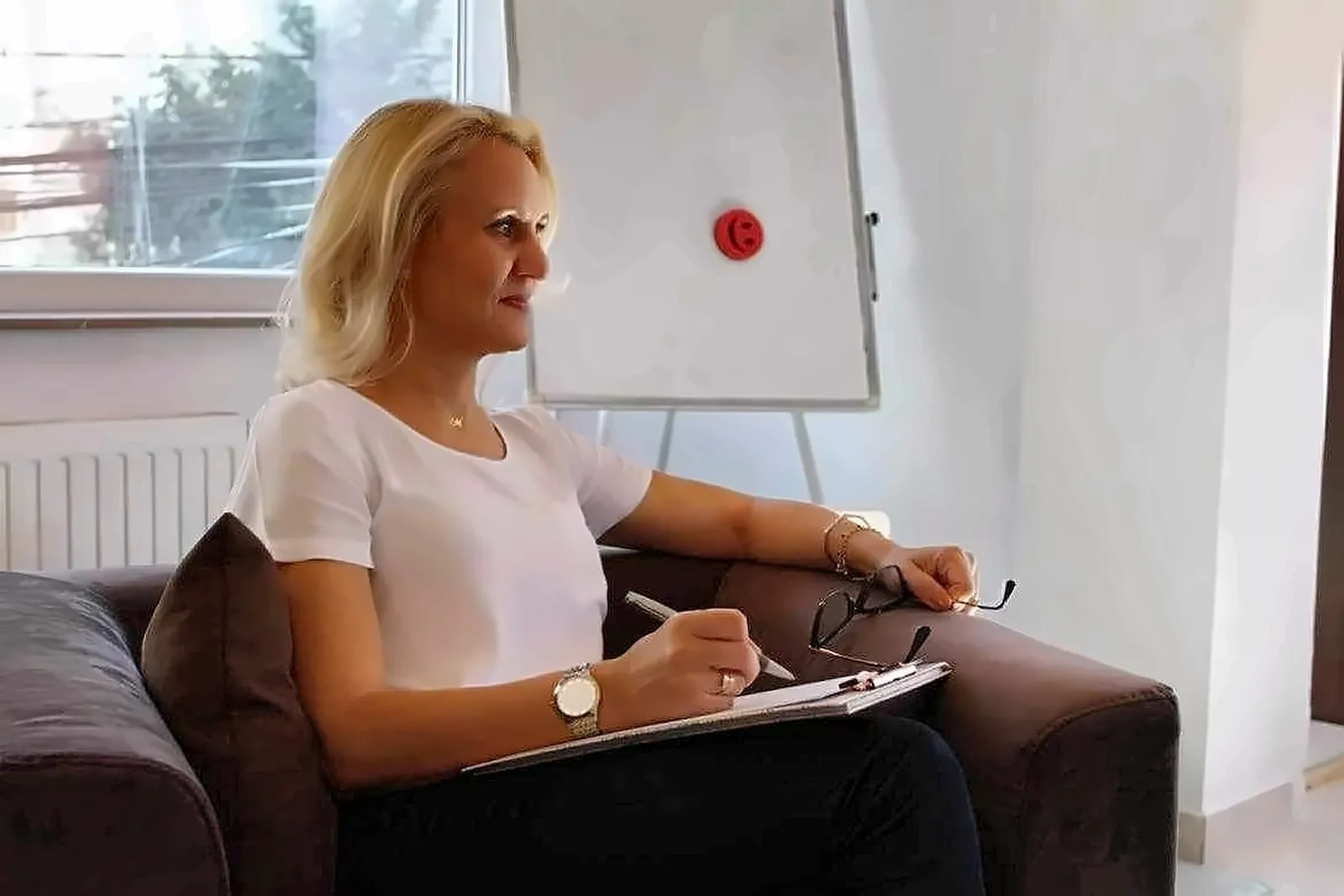 Psiholog Monica Nazîru în fotoliul din cabinet, luând notițe în timpul unei ședințe